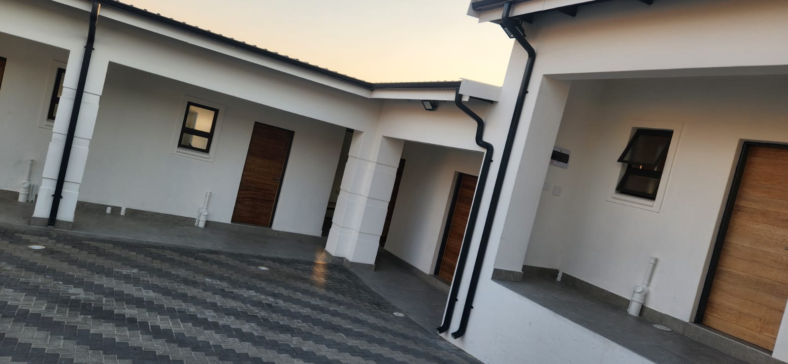 Completed black gutters and corner downpipes on a white townhouse complex